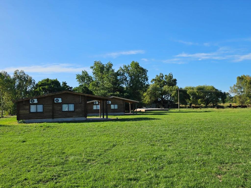 a log cabin in a field with a grass field at Campo Cuyen, Cabañas in Lobos