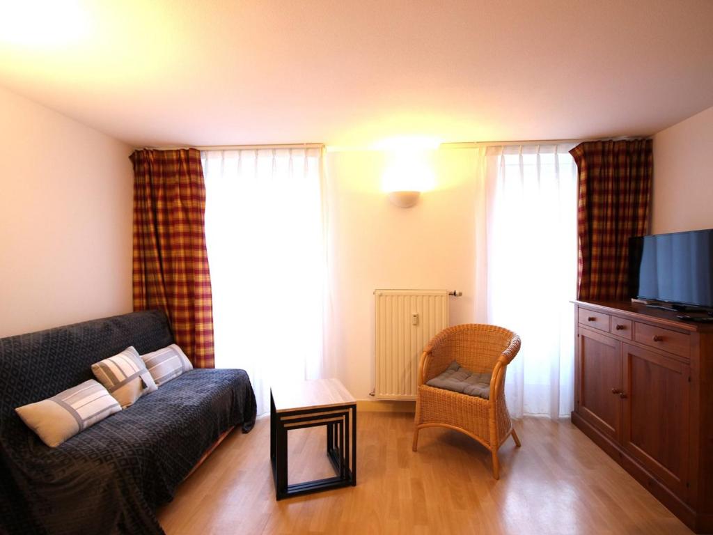 un salon avec un canapé et une chaise dans l'établissement Charmant T2 Bis avec Wi-Fi, Proche Thermes et Commodités à La Bourboule - FR-1-608-266, à La Bourboule