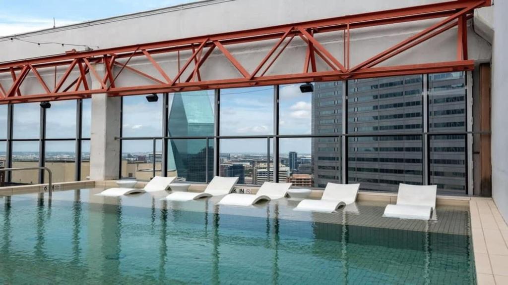 a pool with white lounge chairs in a building at 16th FL Bold CozySuites with pool, gym, roof #4 in Dallas