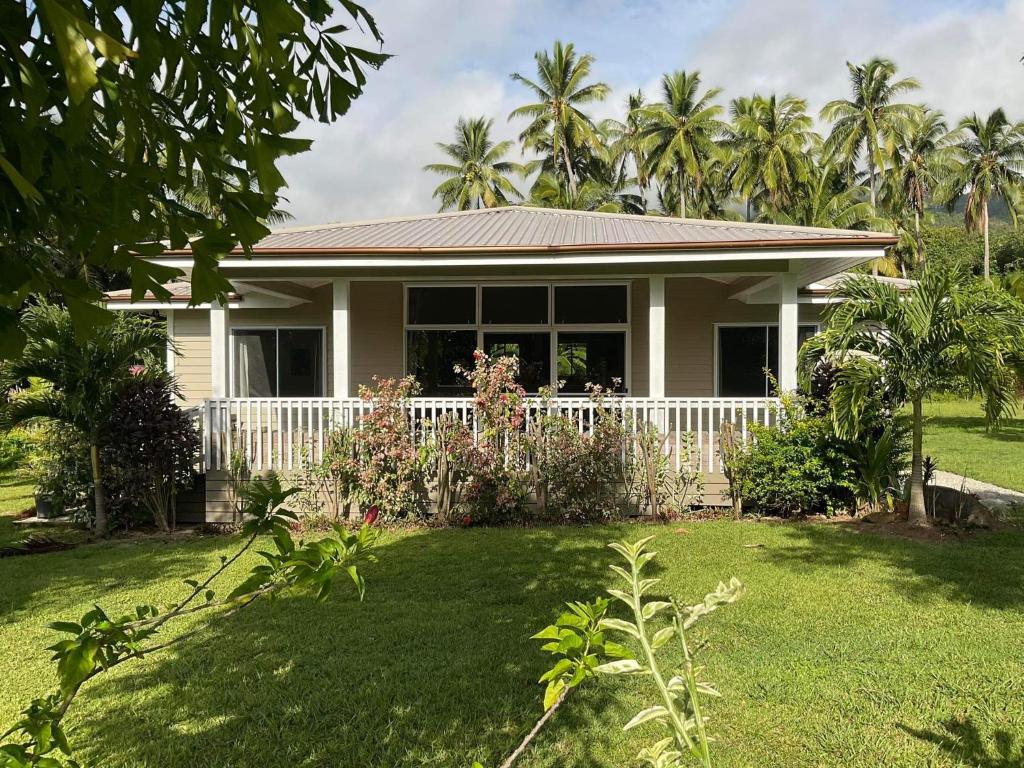 a house with a white fence in a yard at Are'ora - the house for living in Rarotonga