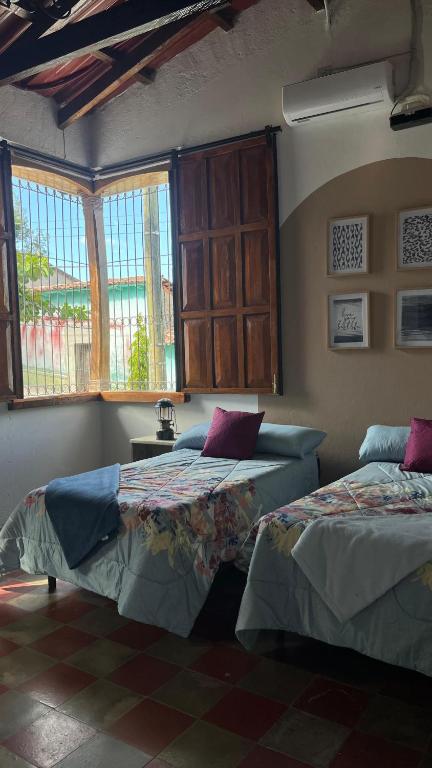 a room with two beds in a room with windows at Donde Polo Hostal in Suchitoto