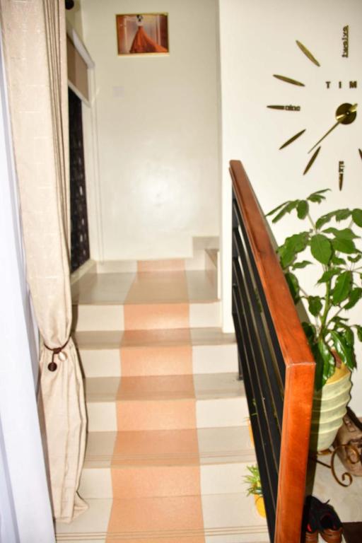 um corredor com uma escada com uma planta e um relógio na parede em Divine apartments Ntinda em Kampala
