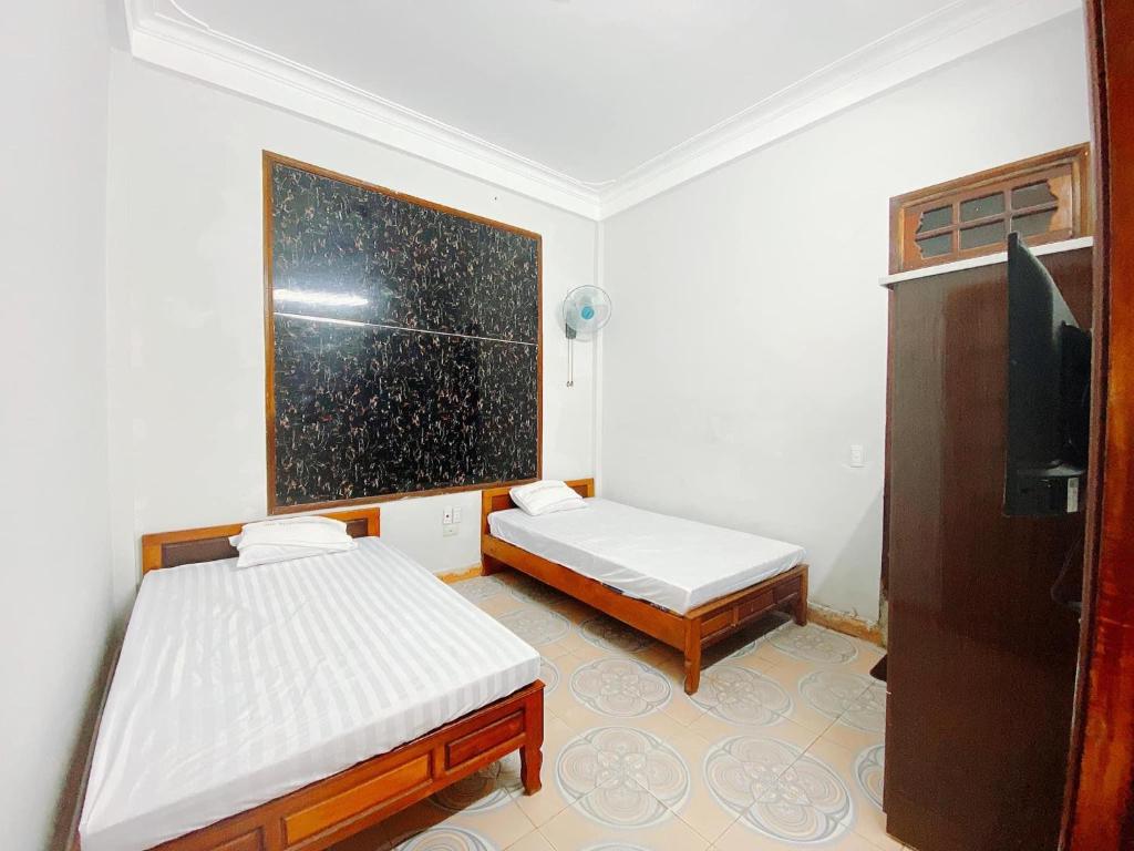 a small room with two beds and a television at CHUNG BẰNG MOTEL in Hương Hóa