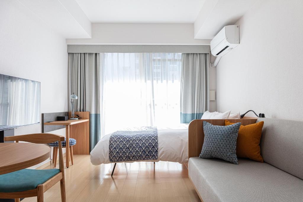 una camera d'albergo con letto e divano di yksi STAY ＆ APARTMENT OSAKA ad Osaka