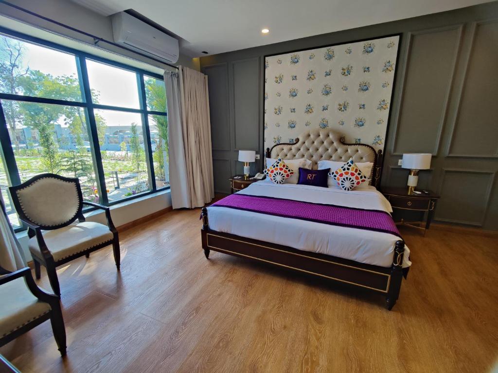 - une chambre avec un lit, une chaise et des fenêtres dans l'établissement RT Grace Royal Taj Hotel Sukkur, à Kalar Goth