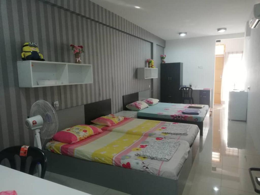 a bedroom with two beds and a fan at CY Homestay in Kampar