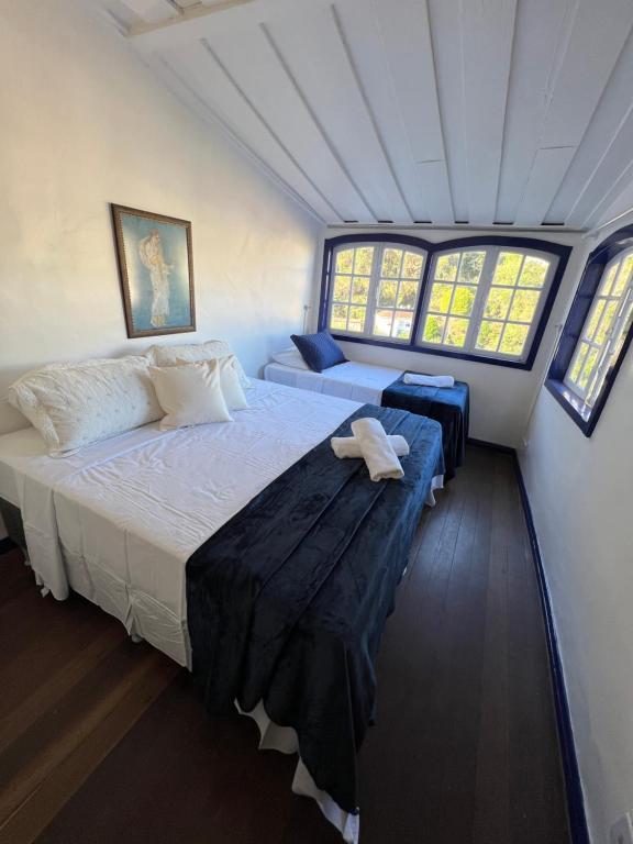 a bedroom with a large bed and two windows at History Hostel in Ouro Preto
