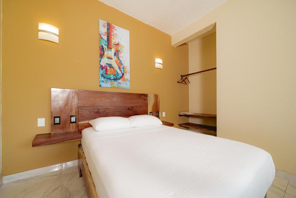 a bedroom with a white bed and a guitar painting on the wall at Guitarra Inn in Puerto Escondido