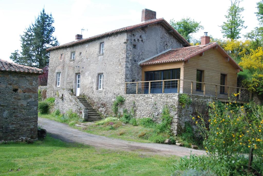 an old stone building with a porch and a house at Le Moulin Moreau in Saint-Pierre-des-Échaubrognes