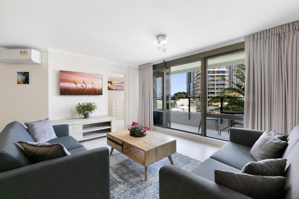 a living room with two couches and a table at Bright 2-Bed with Pool, Spa & Tennis Court in Gold Coast