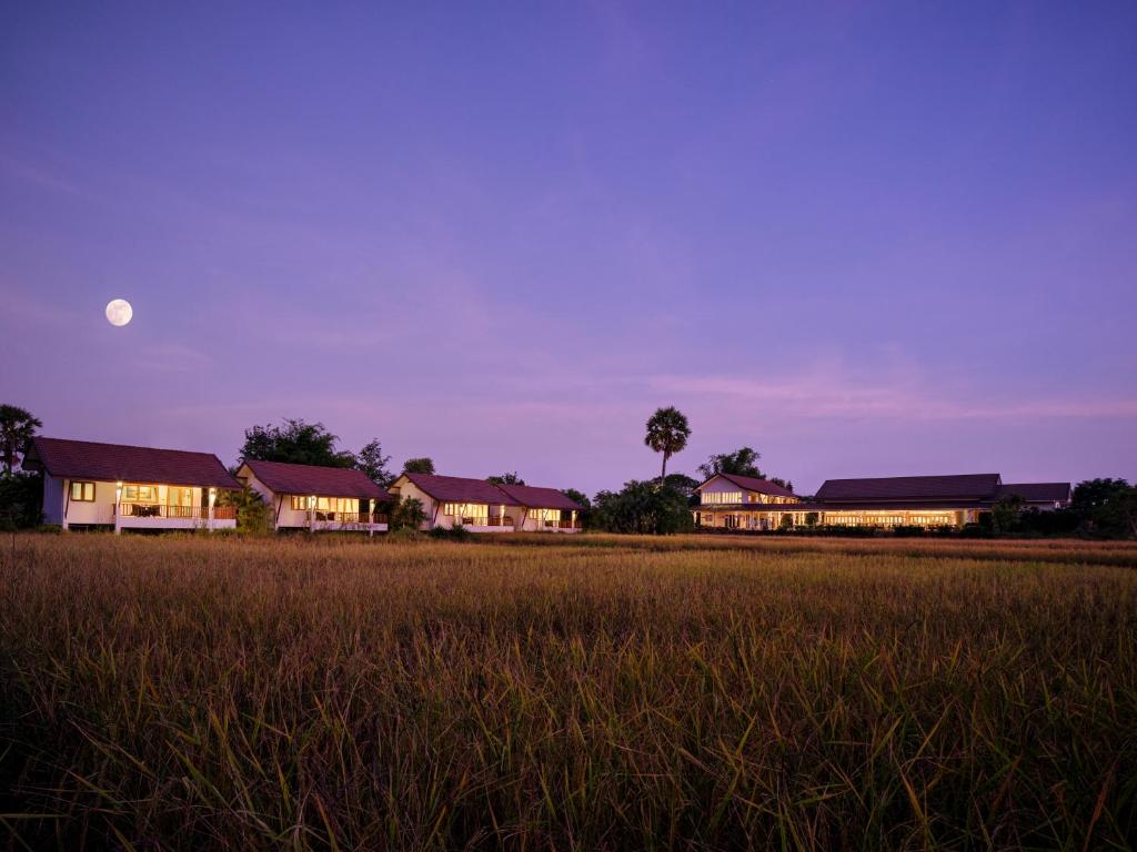eine Gruppe von Häusern auf einem Feld mit dem Mond am Himmel in der Unterkunft Pimali Resort & Training Centre in Nong Khai