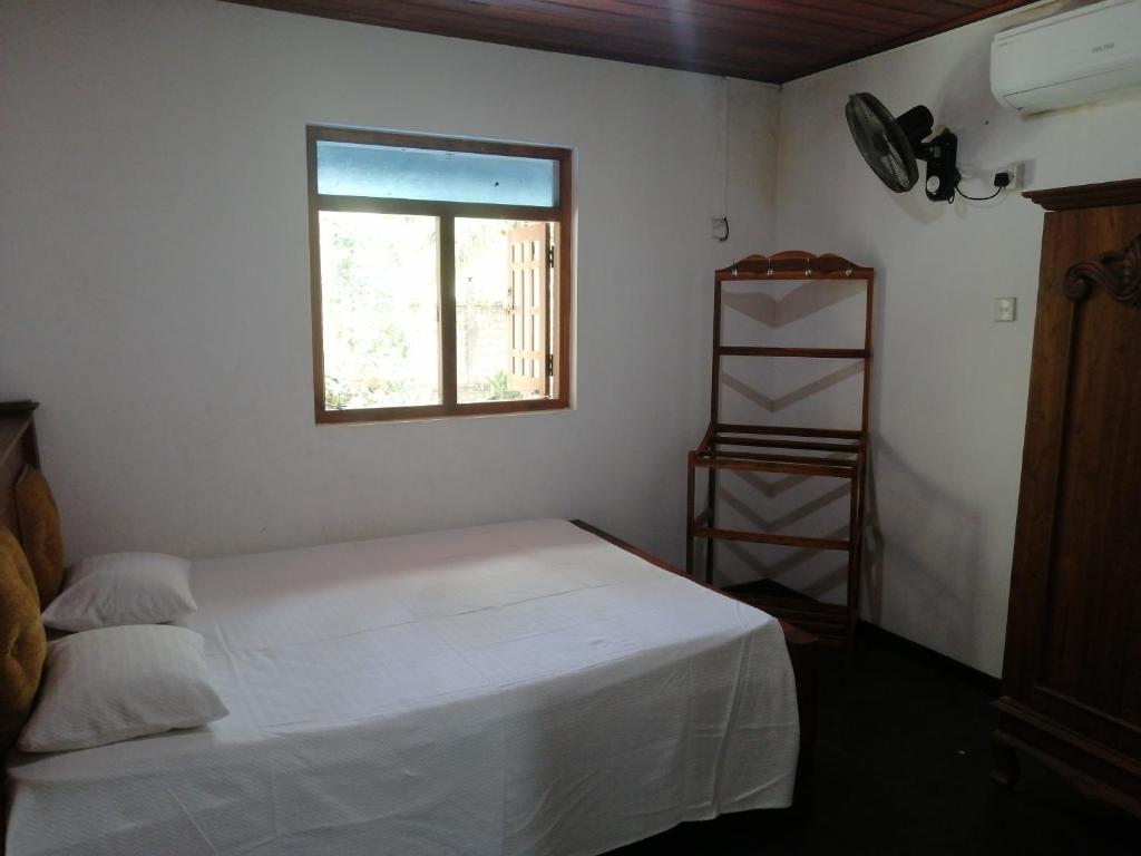 ein Schlafzimmer mit einem weißen Bett und einem Fenster in der Unterkunft Geeth Lanka River Resort in Matale