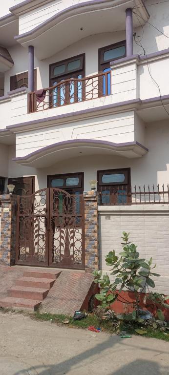 une maison blanche avec un portail et un garage dans l'établissement The New Grand INN, à Gorakhpur