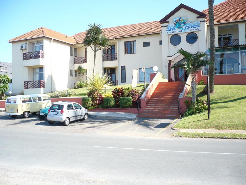 a building with cars parked in a parking lot at Sea Fever Lodge in Umkomaas