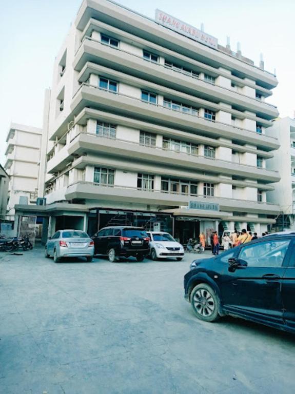 un parking avec des voitures garées devant un bâtiment dans l'établissement Hotel Shane Avadh , Ayodhya, à Ayodhya