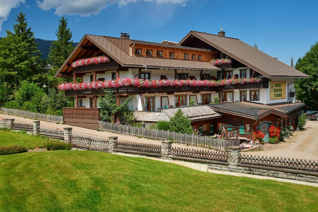 a large house with flowers on the side of it at Biohotel Walserstuba in Riezlern