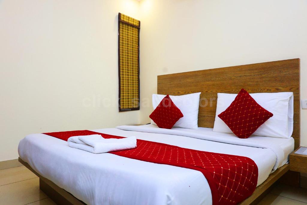 um quarto com uma cama grande e almofadas vermelhas e brancas em Hotel Park Residency By BYOB Hotels em Nova Deli