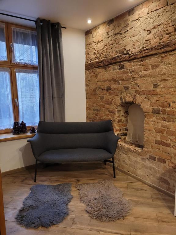 トルンにあるKlimatyczny apartament na starówceのリビングルーム(レンガ造りの暖炉付)のソファ