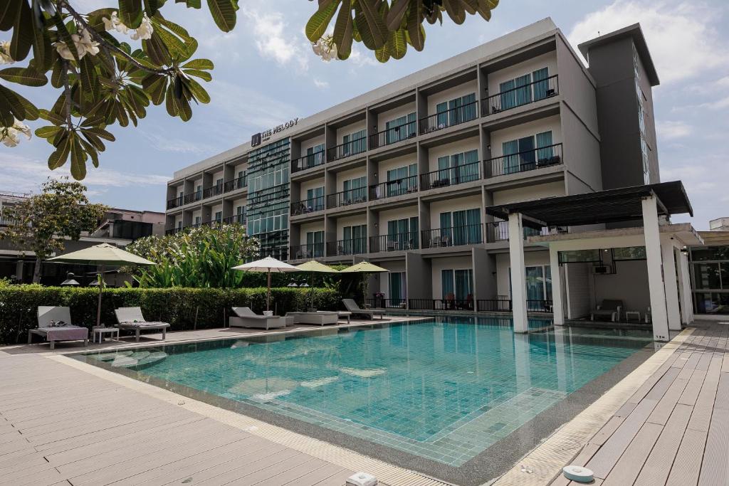 カタビーチにあるThe Melody Phuket - SHA Extra Plusの建物の前にスイミングプールがあるホテル