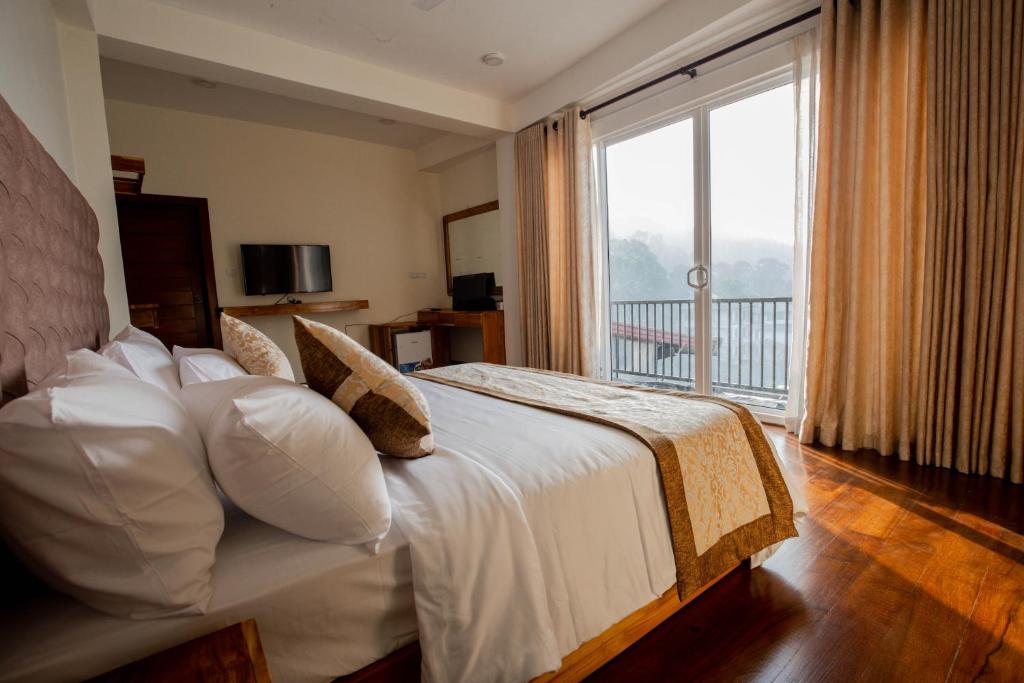a bedroom with a bed with a large window at Manthra Leisure in Kandy