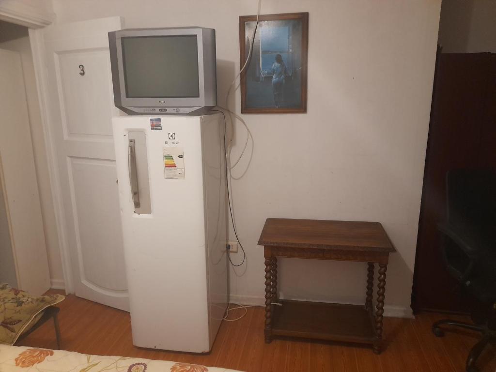 a television on top of a refrigerator with a table at Hostal batuco in Viña del Mar