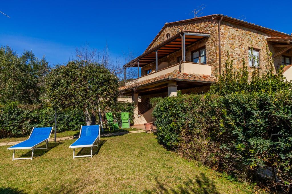 duas cadeiras azuis sentadas na relva em frente a uma casa em Villa Rosanna em Castiglione della Pescaia