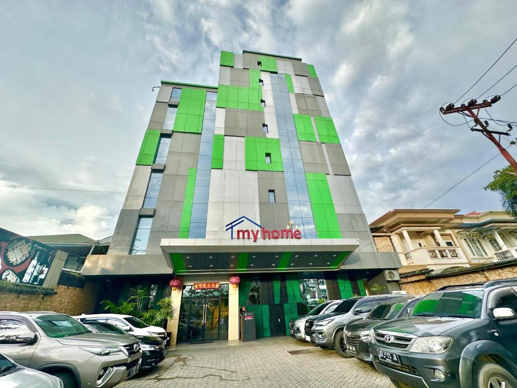 un edificio con coches estacionados en un estacionamiento en My Home Hotel Pontianak, en Pontianak