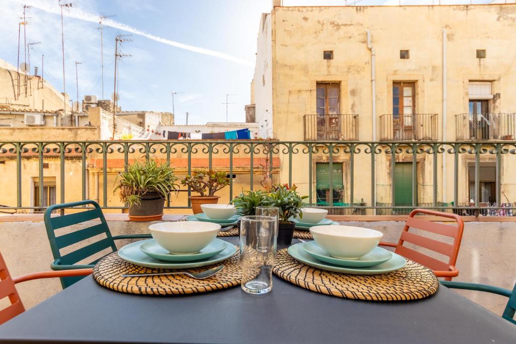 una mesa con tazones y platos en la parte superior de un balcón en GROOOVY Dúplex amb Terrassa, en Tarragona
