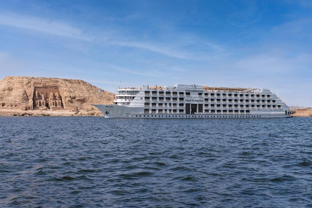 Steigenberger Omar El Khayam Nile Cruise - Every Monday from Aswan for 07 & 04 Nights - Every Friday From Abu Simbel for 03 Nights في أسوان: سفينة الرحلات البحرية في الماء بجانب مبنى