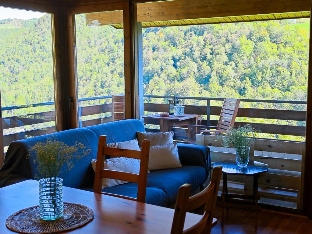 uma sala de estar com um sofá azul e uma mesa em Can Geneta em Molló