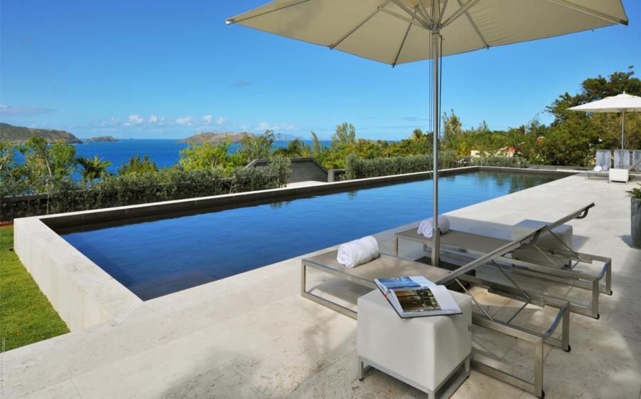a swimming pool with a chair and an umbrella at Luxury Vacation Villa 13 in Pointe Milou