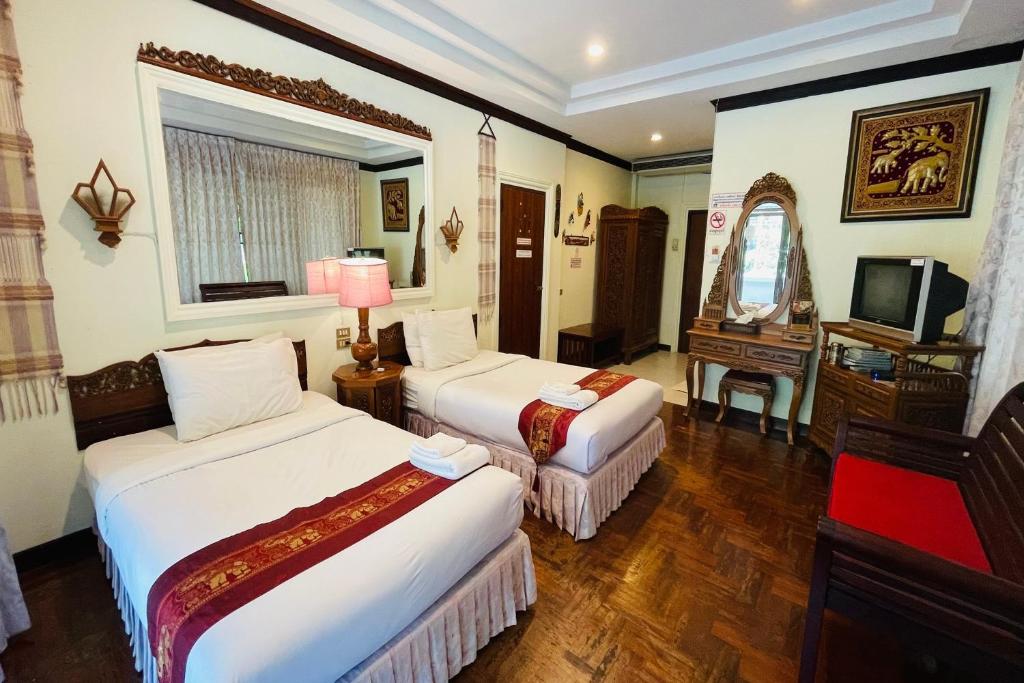 a hotel room with two beds and a television at Baan Rim Kwai Paerimnam Resort in Kanchanaburi