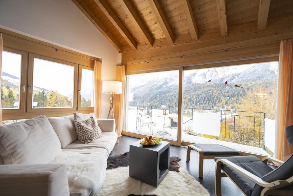 a living room with a white couch and large windows at Chasa Capricornin in Scuol