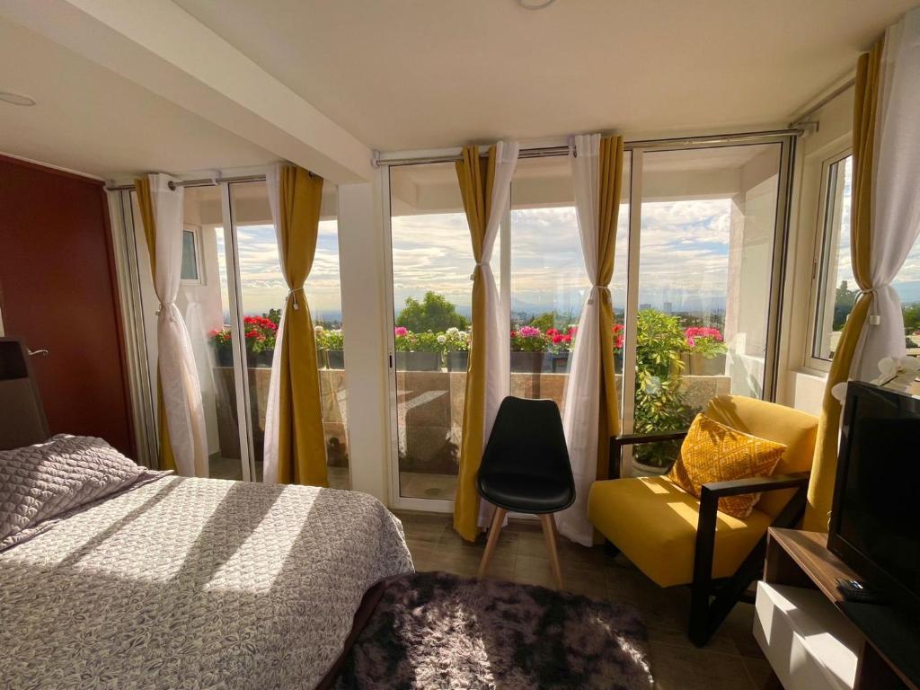 ein Schlafzimmer mit einem Bett, einem gelben Stuhl und einem Fenster in der Unterkunft ¡Intimo, pequeño, confortable, mejor que hotel! in Mexiko-Stadt