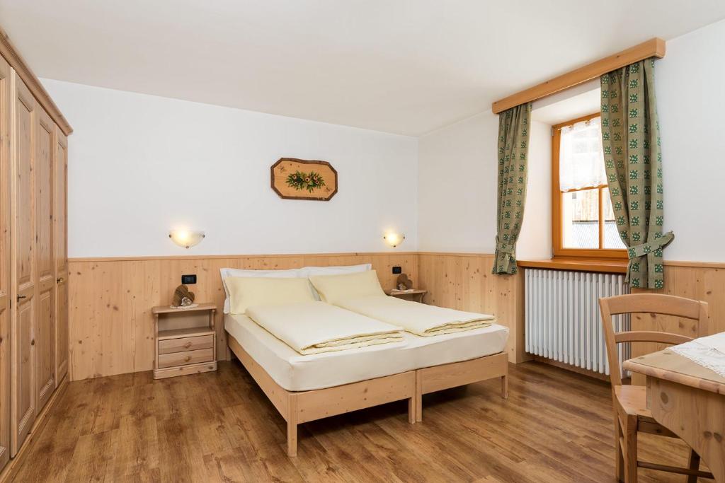 1 dormitorio con cama, escritorio y ventana en Cesa Raggio di Sole Bilocale, en Livinallongo del Col di Lana