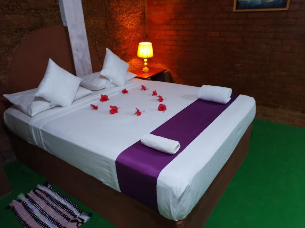 a bed with red rose petals on it at Hotel Vinchenso in Kaduwela