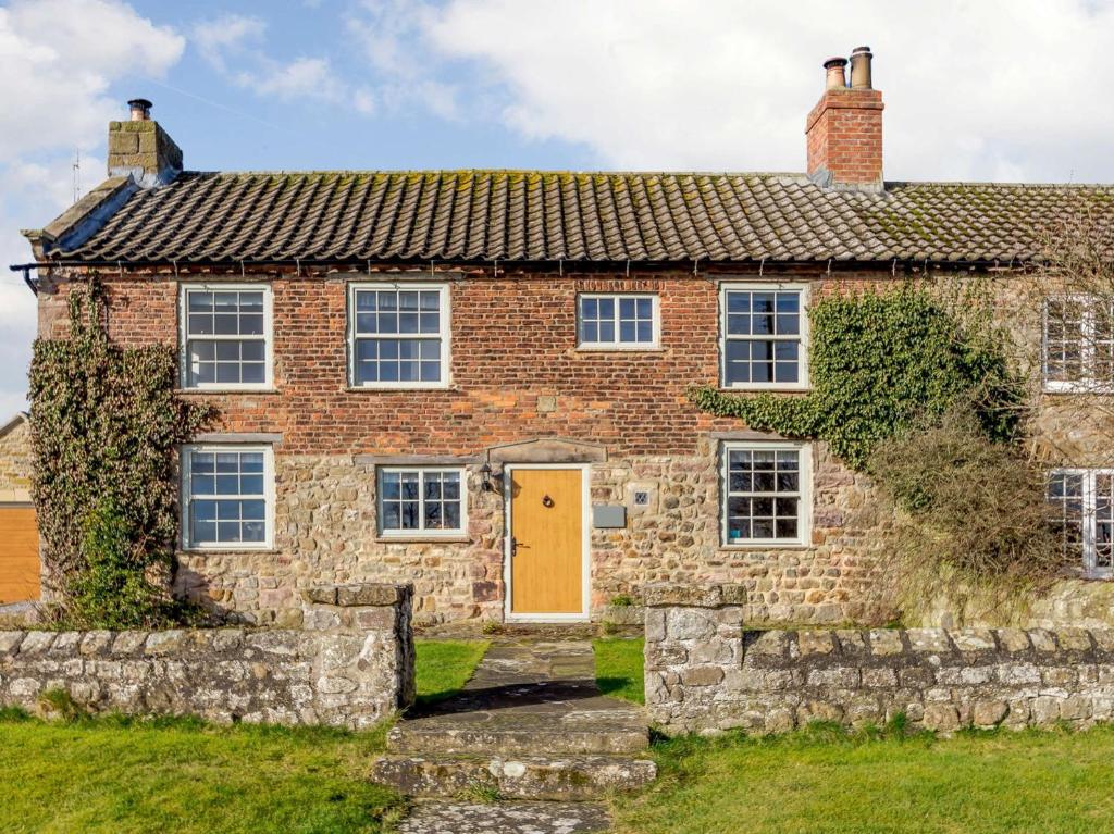 an old brick house with a yellow door at 3 Bed in Bedale 81375 in Hackforth