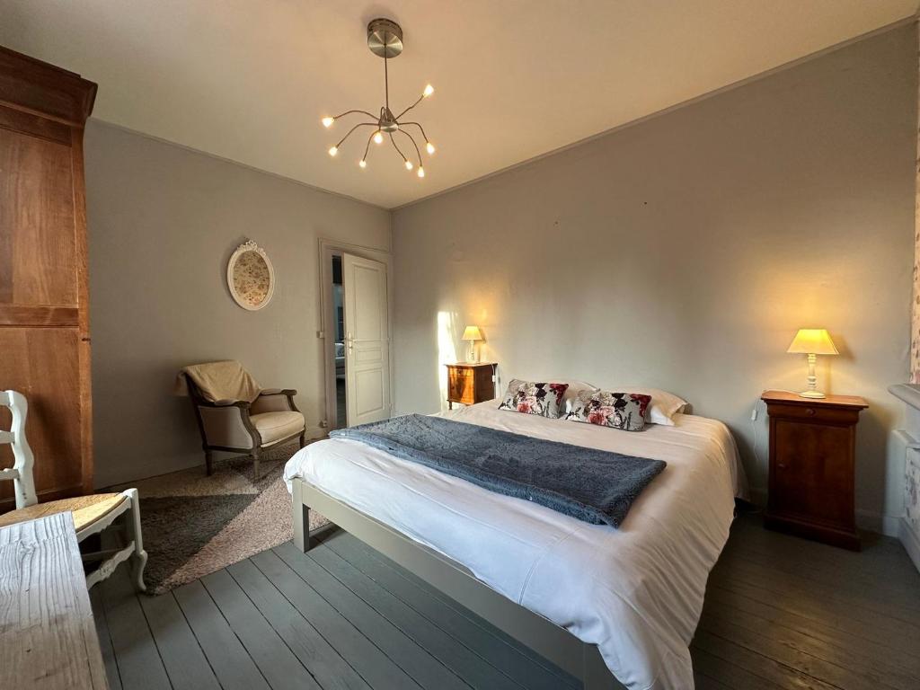 ein Schlafzimmer mit einem großen Bett und einem Stuhl in der Unterkunft Maison Kérity with Jacuzzi – Terrace in Paimpol