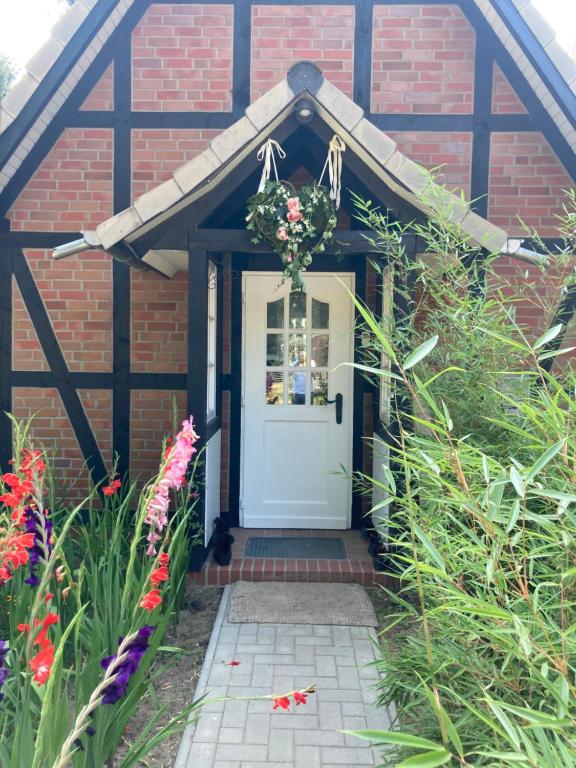 een stenen huis met een witte deur en bloemen bij Haus am Teich in Worpswede