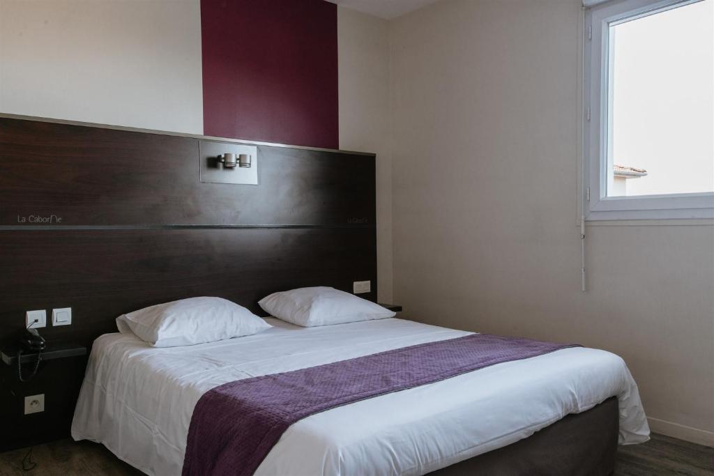 une chambre avec un grand lit avec une grande tête de lit dans l'établissement Hotel-Restaurant La Caborne, à Limonest