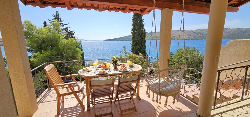 a table on a balcony with a view of the water at Jacuzzi, summer kitchen, gardens, 20m to beach - Villa Casa Plaza in Seget Vranjica