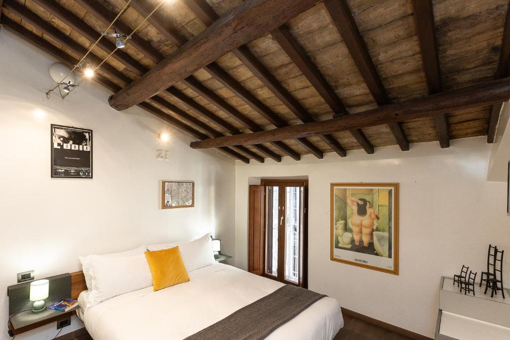 a bedroom with a white bed and wooden ceilings at Mou Trastevere House by Rental in Rome in Rome