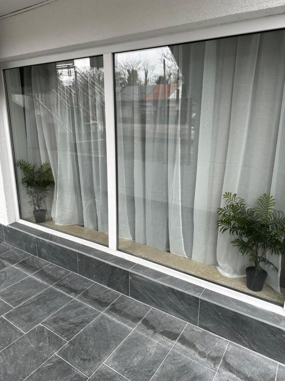 een raam met witte gordijnen en twee potplanten bij Apartment Lana - FREE parking&great location in Zagreb