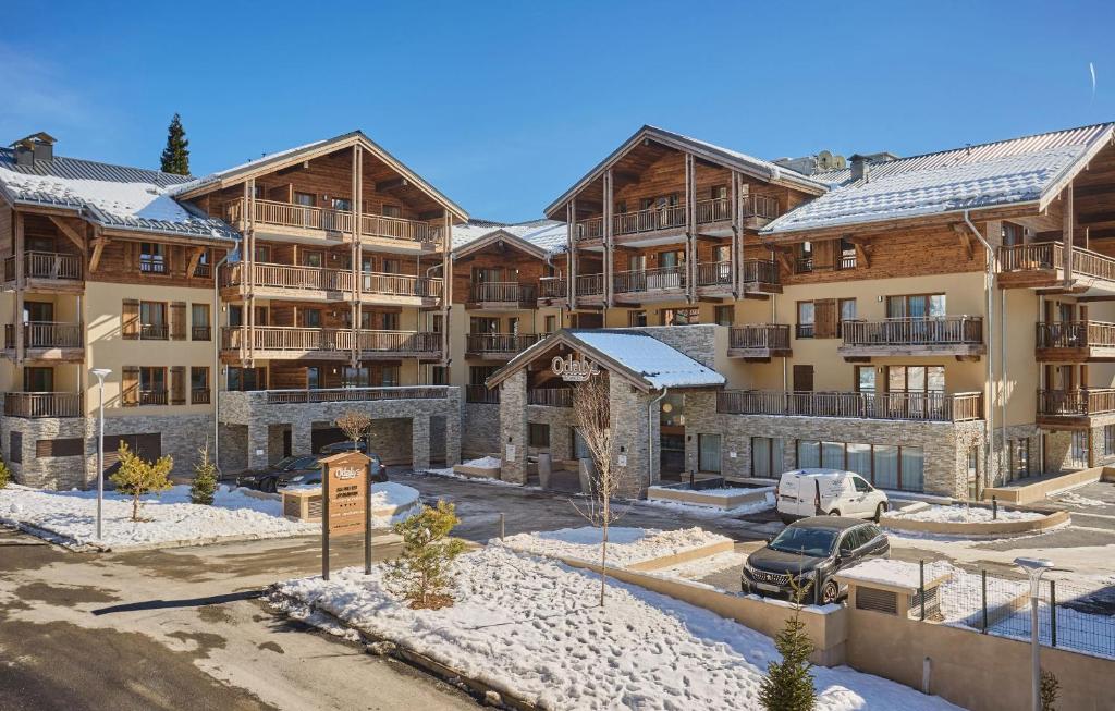 un immeuble d'appartements avec un parking en face de celui-ci dans l'établissement Résidence Prestige Odalys Le Mont d'Auron, à Auron