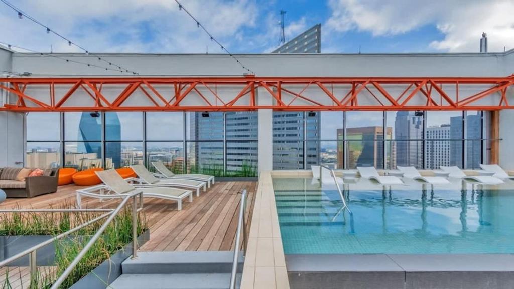 uma piscina no telhado de um edifício com cadeiras brancas em 18th FL Stylish CozySuites with roof pool, gym #2 em Dallas