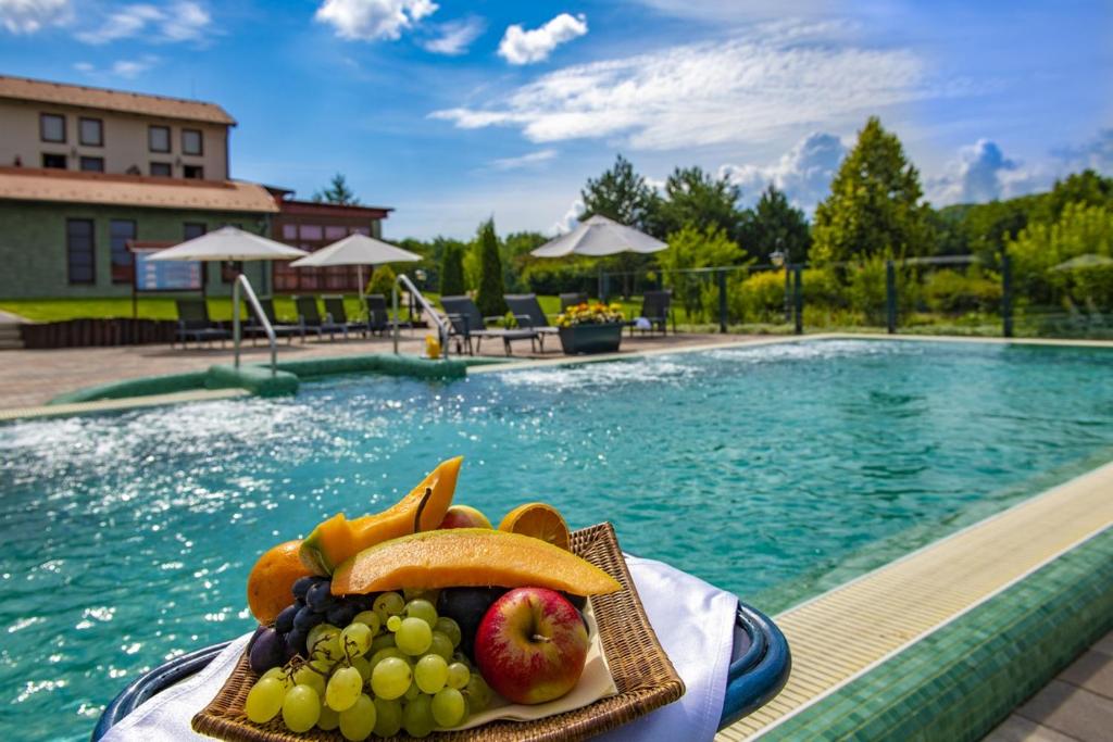 a plate of fruit on a table next to a swimming pool at Hotel Forest Hills in Zirc