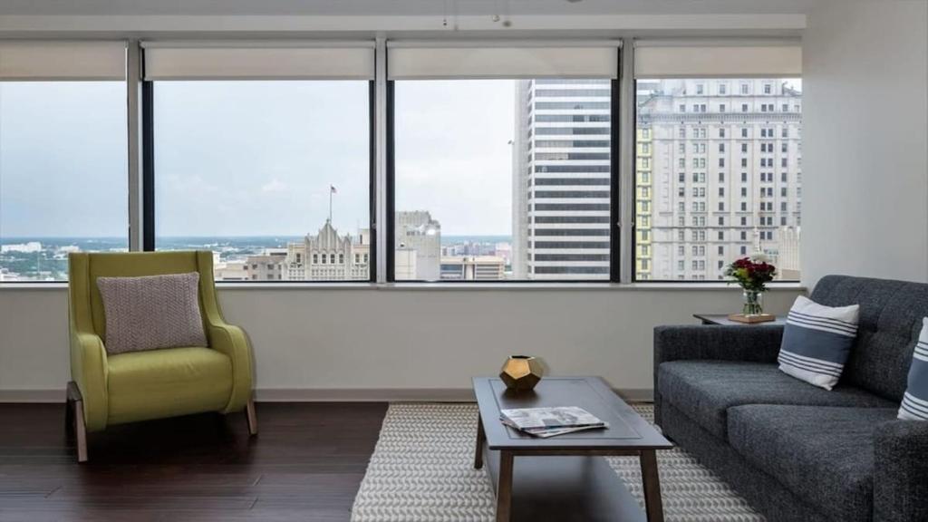 a living room with a couch and a chair and windows at CozySuites TWO Condos with sky Pool in Dallas in Dallas