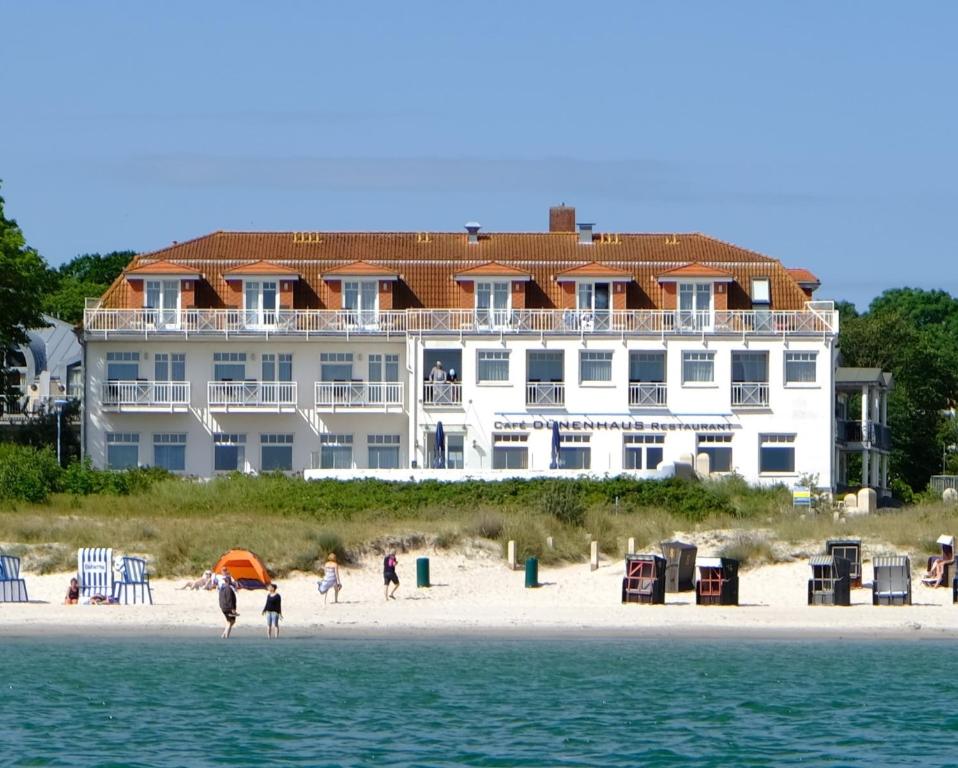 a large building on the beach with people on the beach at Strandhotel Dünenhaus in Juliusruh