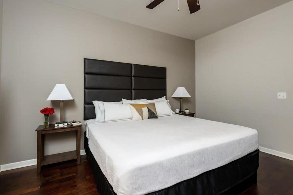 een slaapkamer met een groot wit bed met een zwart hoofdeinde bij Cozysuites TWO Sunny and Urban 2BR Apartment in Dallas