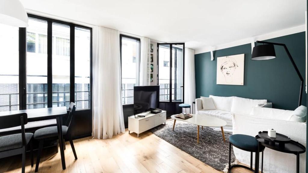 un salon avec un canapé blanc et une table dans l'établissement Bright & renovated 3BD for 8 guests in Le Marais!, à Paris